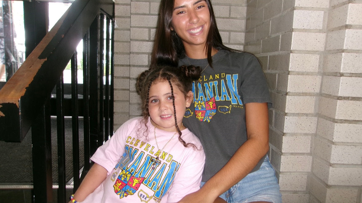 Two people sitting on a staircase wearing matching 'Cleveland' t-shirts.